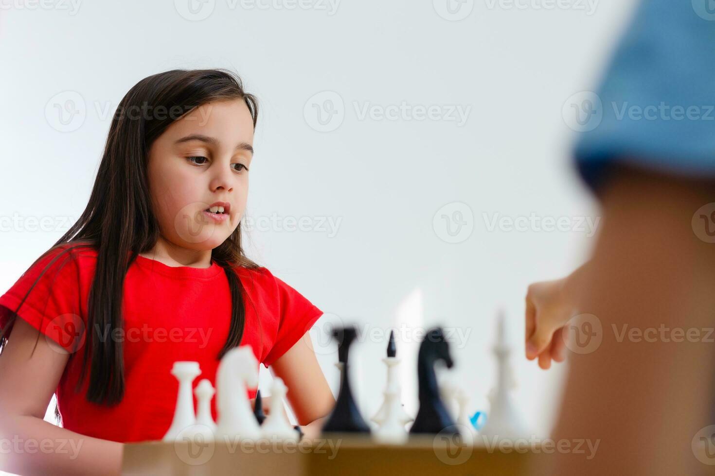 pequeno menina jogando xadrez às uma mesa foto