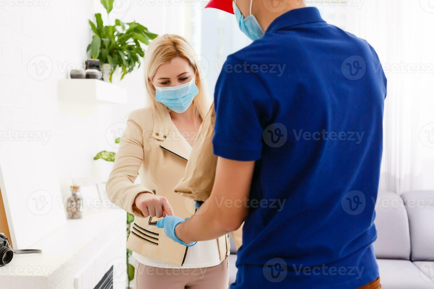 homem a partir de Entrega serviço dentro vermelho boné, dentro protetora mascarar e luvas dando Comida ordem e segurando caixas sobre branco fundo foto