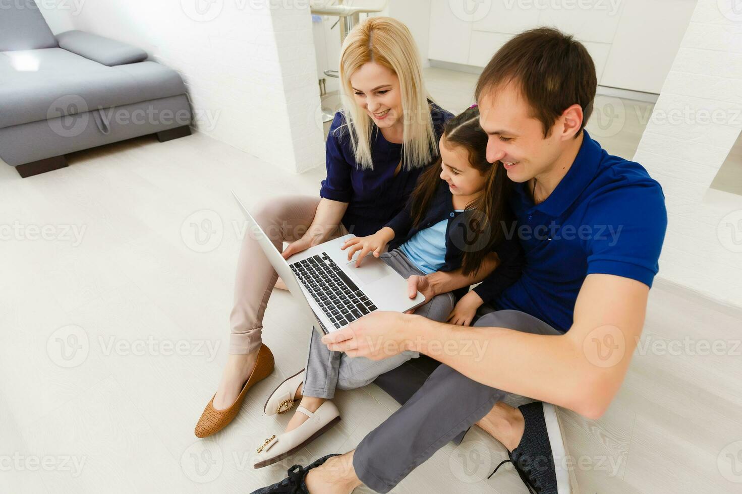 família topo Visão sentado em chão usando computador portátil computador dentro dela quarto às casa foto
