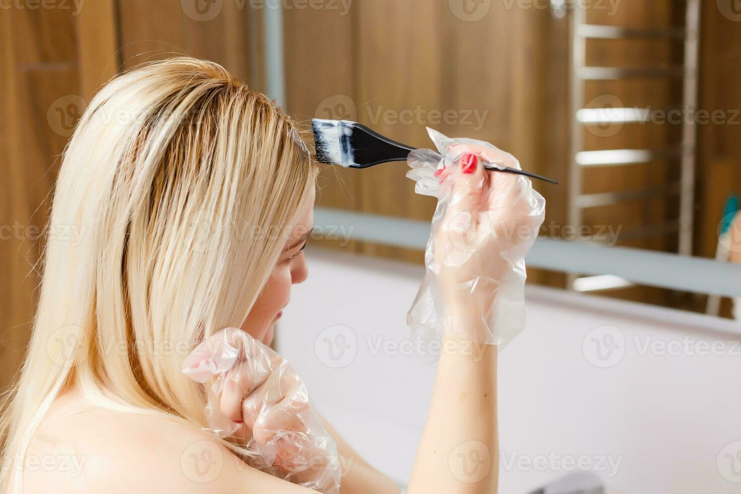 uma meia idade mulher tintas dela cabelo às lar, dentro de casa foto