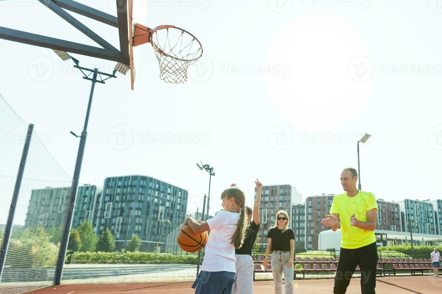 família jogando basquetebol em quadra foto