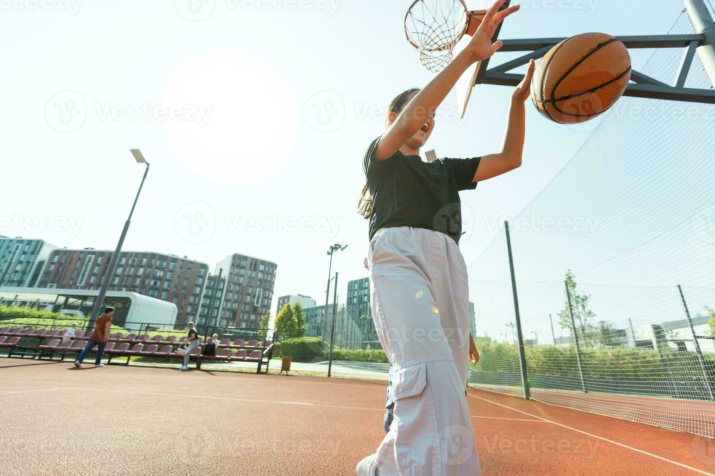 conceito do Esportes, hobbies e saudável estilo de vida. jovem Atlético menina é Treinamento para jogar basquetebol em moderno ao ar livre basquetebol tribunal. feliz mulher foto