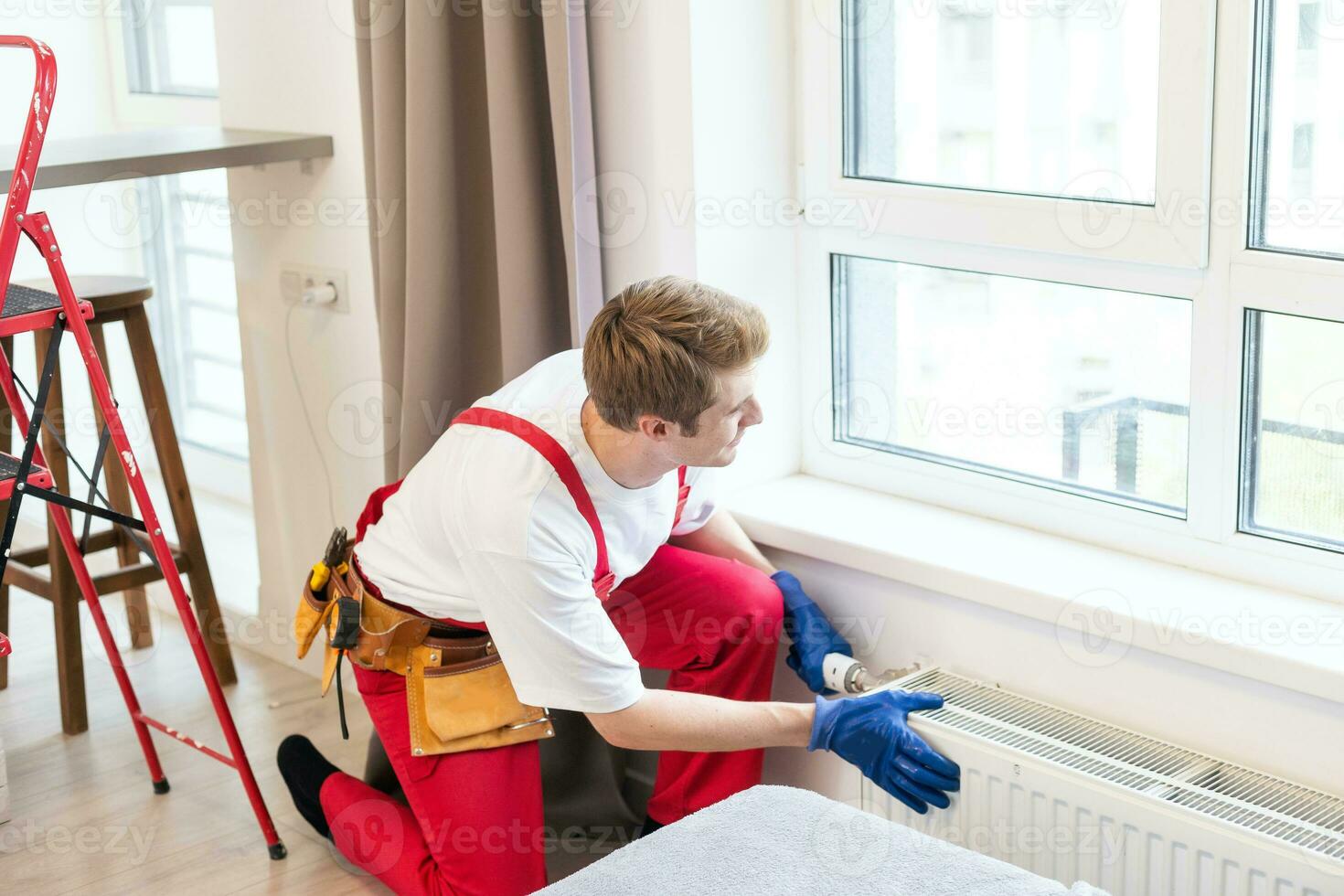 cheio comprimento tiro do dois profissional encanadores, trabalhadores dentro uniforme fixação ou instalando aquecimento radiador. construção, manutenção e reparar conceito. foto