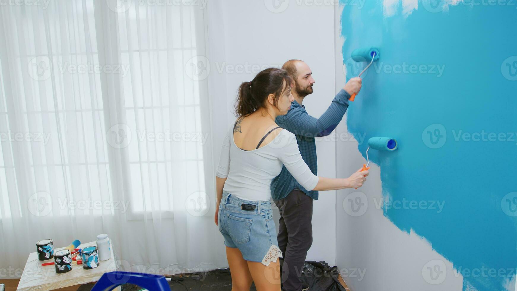 caucasiano casado casal fazendo uma reforma do seus apartamento pintura a paredes com rolo escovar. apartamento redecoração e casa construção enquanto renovando e melhorando. reparar e decoração. foto