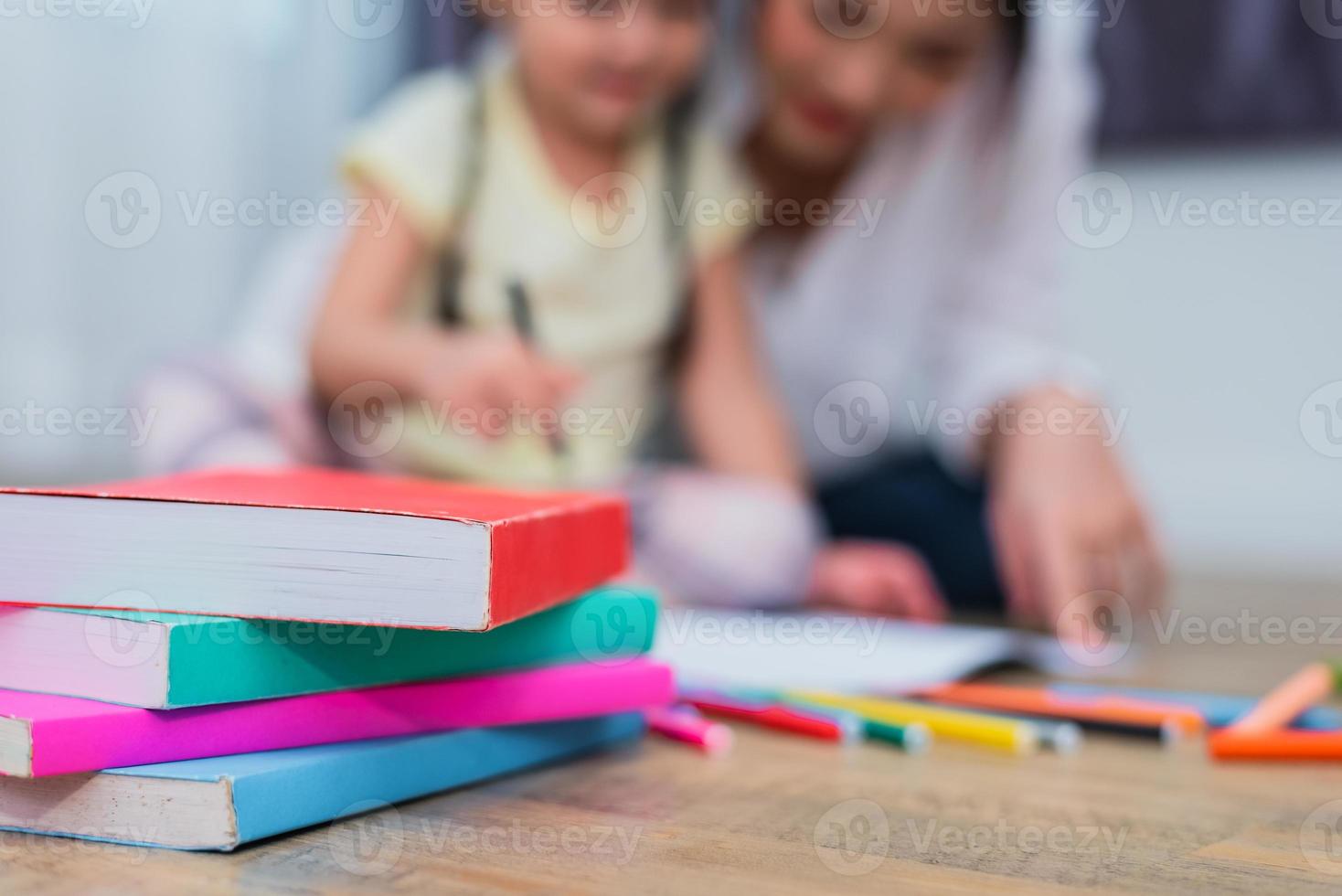 close-up de livros no chão com fundo de mãe e filhos. de volta ao conceito de escola e educação. crianças e tema do professor foto