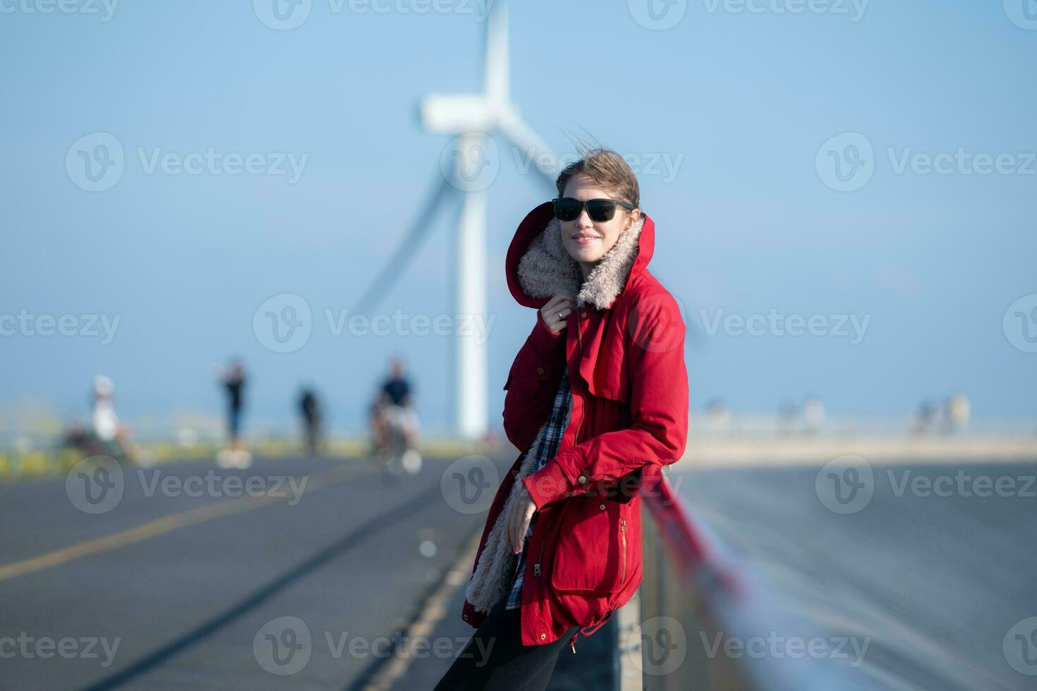 em a fundo do moinhos de vento, uma jovem mulher dentro uma vermelho Jaqueta é desfrutando dela inverno período de férias. foto