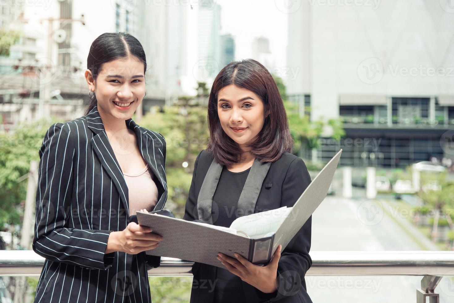 duas jovens empresárias asiáticas olhando para a pasta de arquivo de documentos para analisar o ponto de equilíbrio de lucro ou venda após a comercialização. Funcionários do trabalho em equipe de negócios do conceito de mulheres trabalhadoras de estilo de vida foto