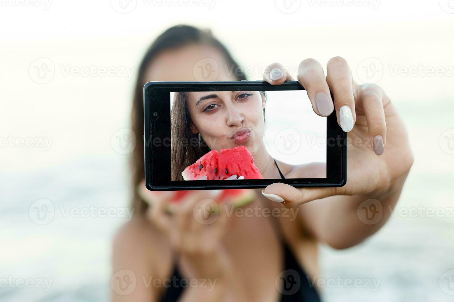 verão período de férias - jovem menina comendo fresco Melancia em arenoso de praia foto