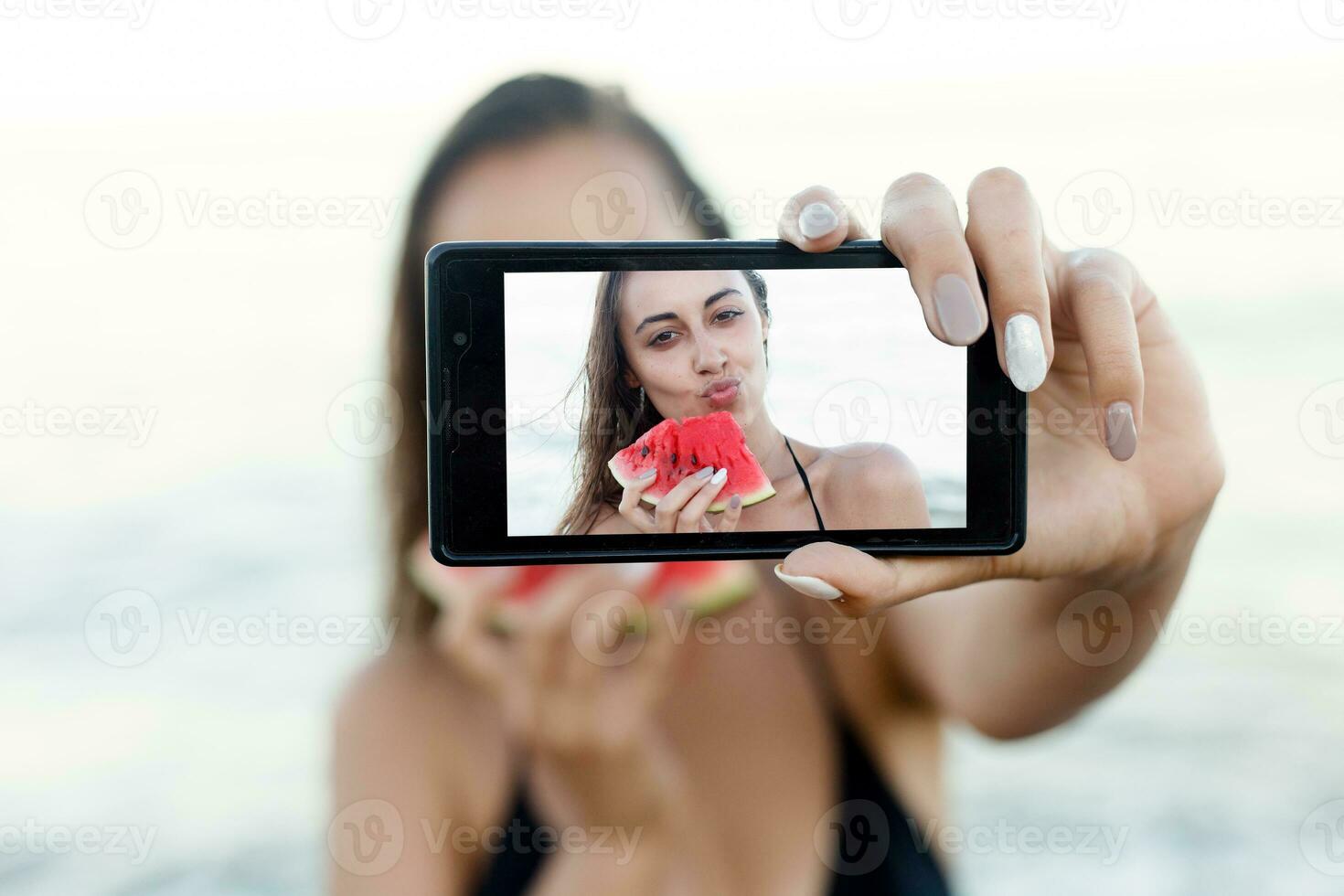 verão período de férias - jovem menina comendo fresco Melancia em arenoso de praia foto