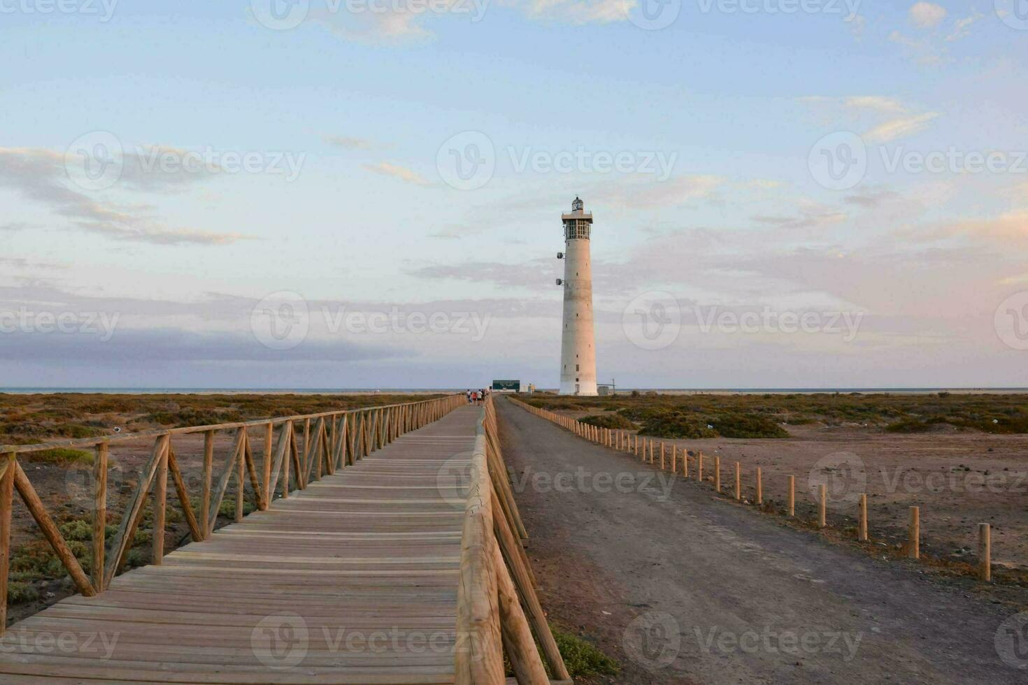 uma de madeira passarela conduz para uma farol dentro a meio do uma deserto foto