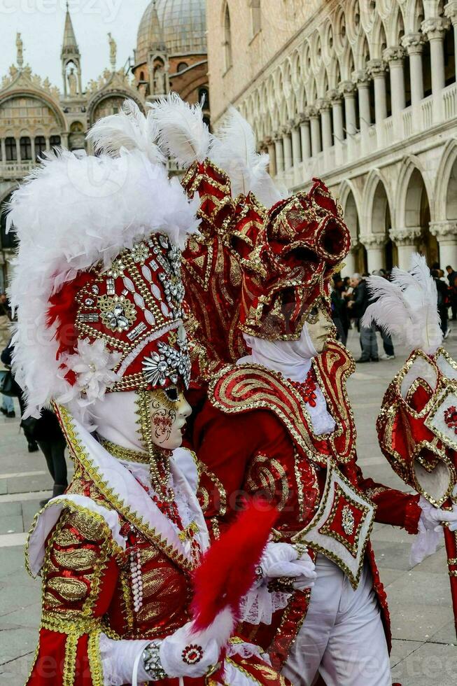 dois pessoas dentro vermelho e branco fantasias com penas foto