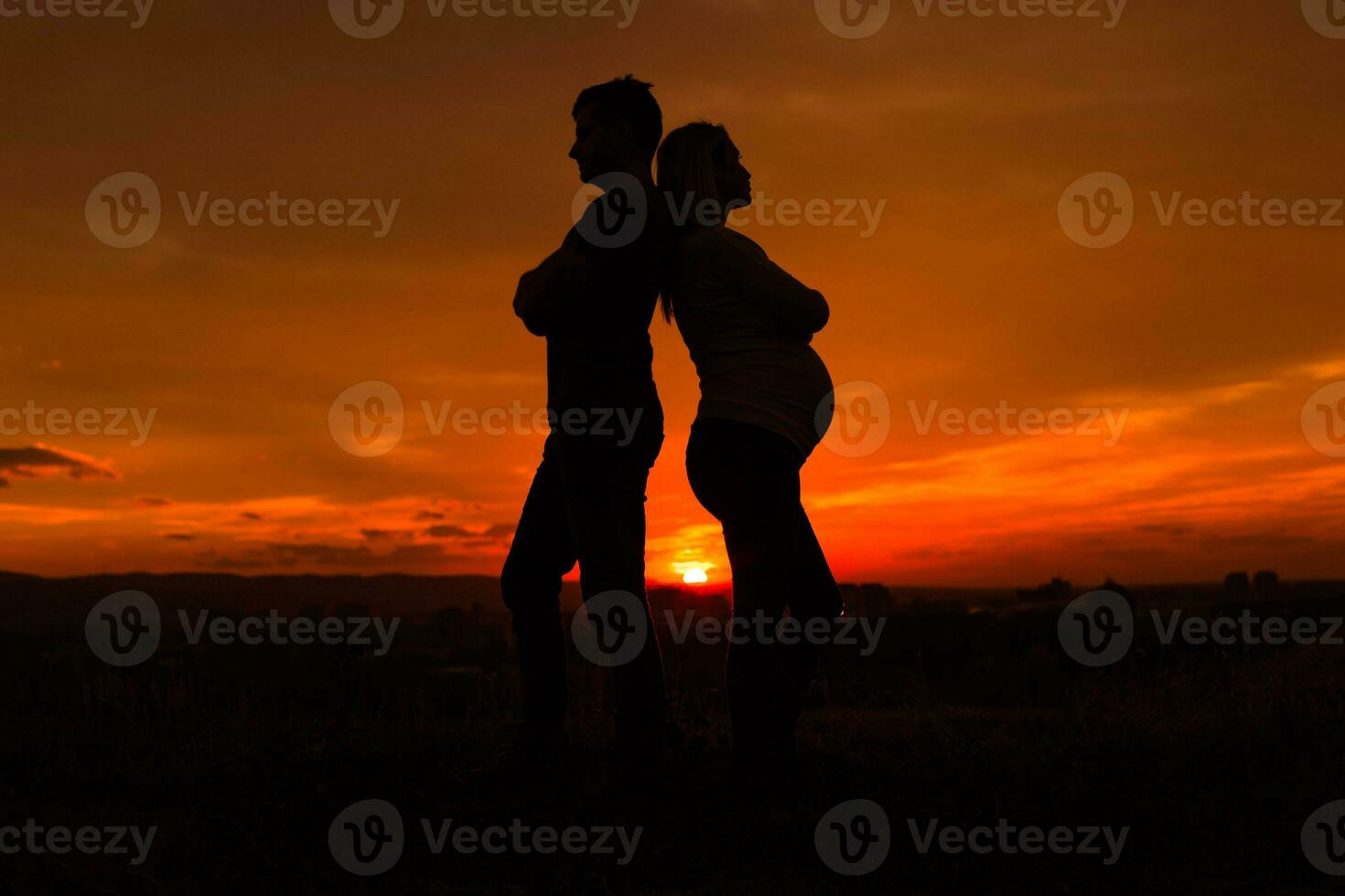 silhuetas do marido e grávida esposa tendo conflito enquanto elas em pé ao ar livre.toned imagem. foto