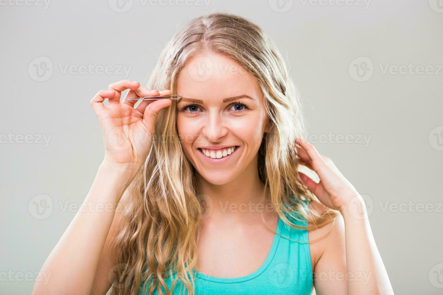 lindo jovem mulher arrancar sobrancelhas em cinzento fundo. foto