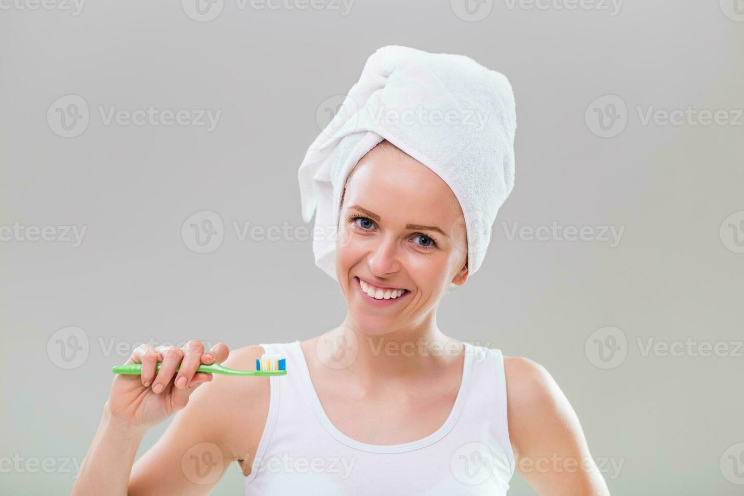 lindo jovem mulher escovar dentes em cinzento fundo. foto