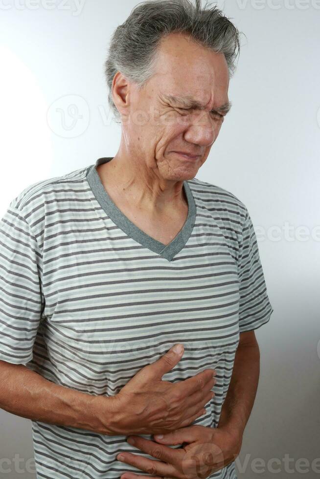 Mais velho maduro homem segurando dele dor de estômago Porque do dor foto