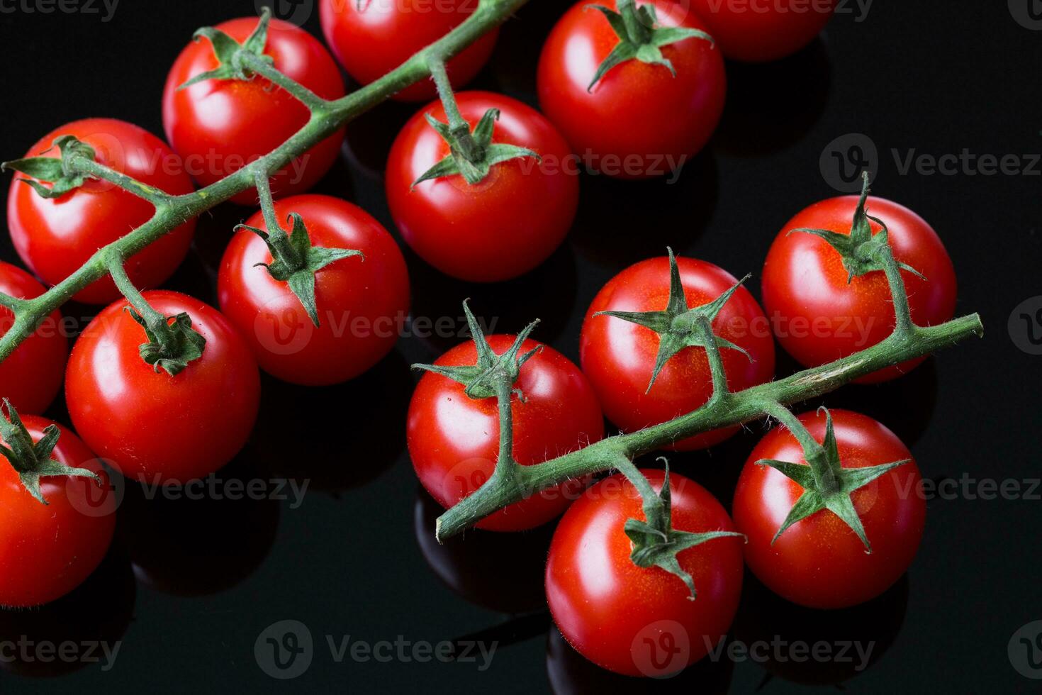 fresco cereja tomates em uma Preto fundo. grupo do fresco cereja tomate em uma Preto fundo foto