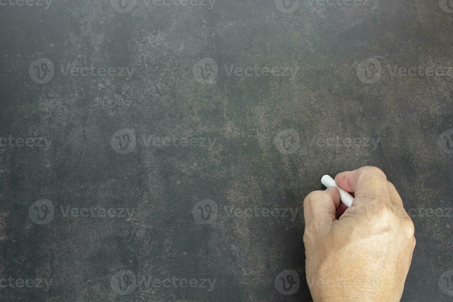 mão masculina escreve em lápis de giz branco sobre um fundo de quadro-negro. copie o espaço. foto