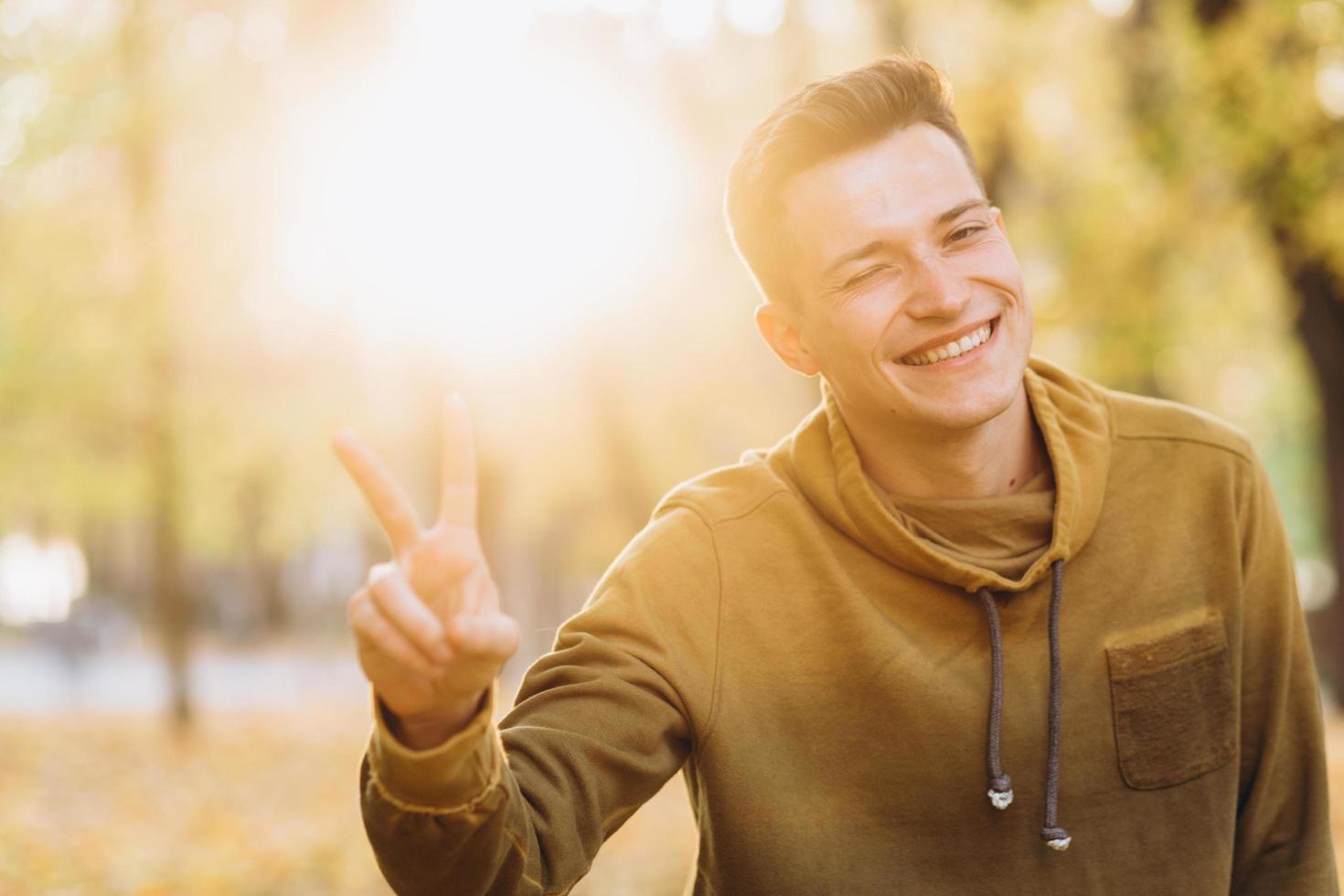 cara bonito sorrindo e mostrando paz no parque de outono foto