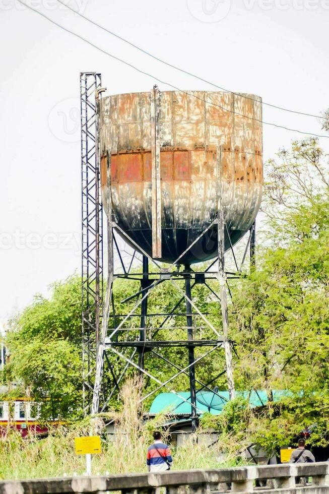 a velho oxidado água torre em a lado do a estrada foto