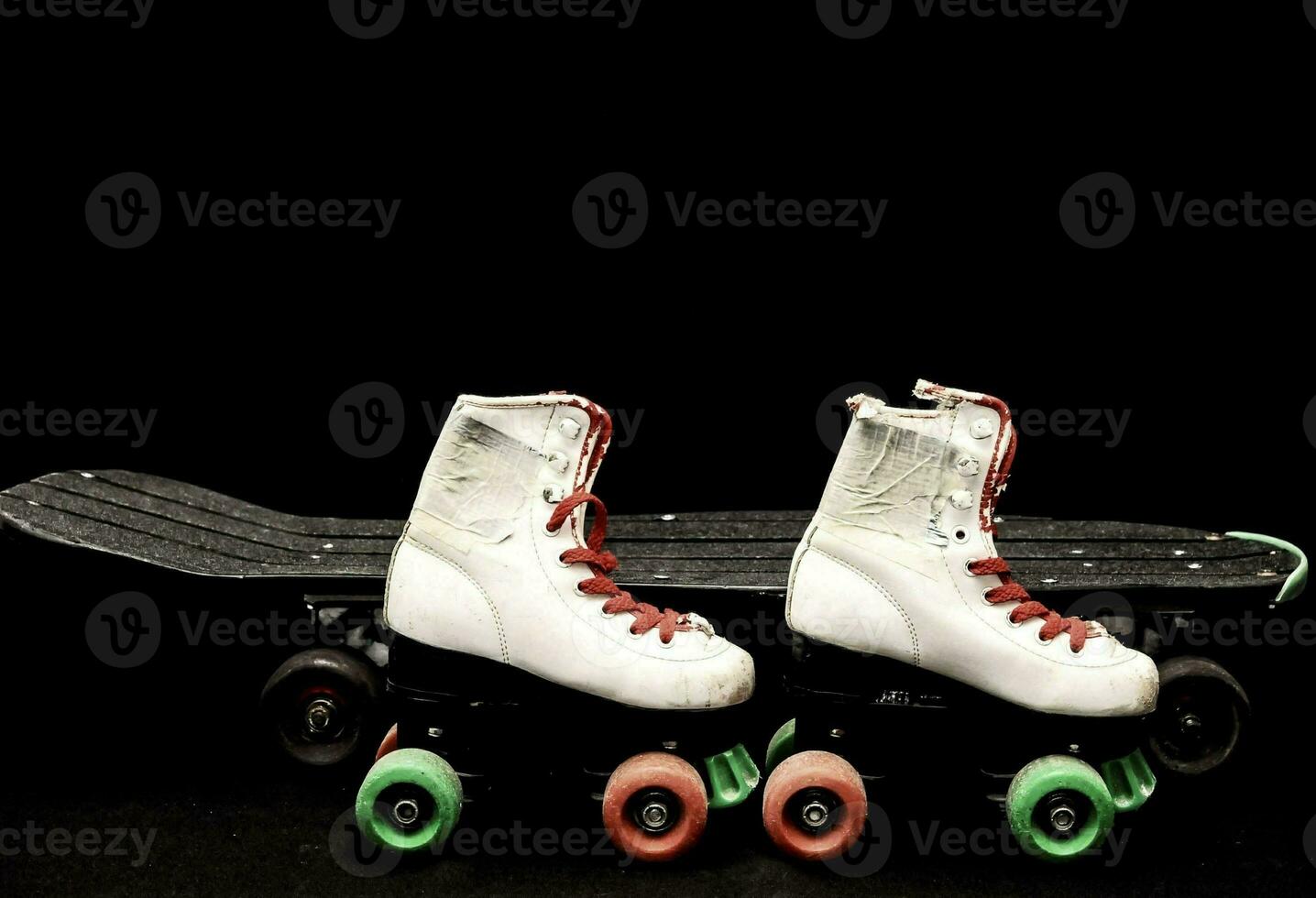 dois rolo patins e uma skate em uma Preto fundo foto