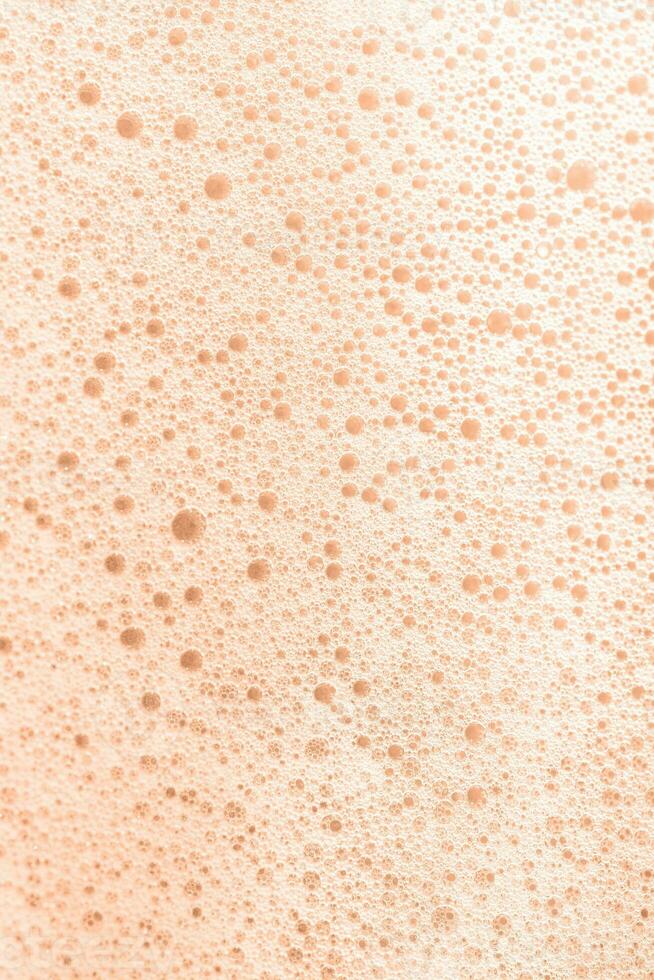 a textura do Sabonete espuma com bolhas em uma pêssego penugem fundo. foto