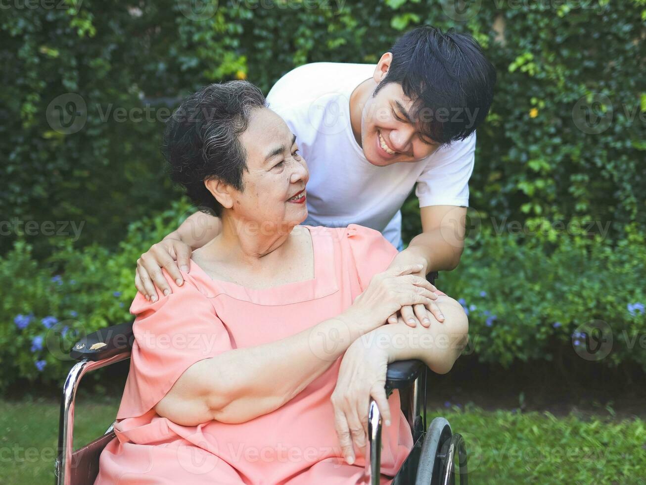 ásia Senior mulher sentado em cadeira de rodas com dela filho dentro a jardim. foto