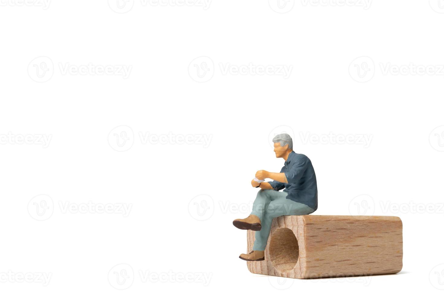 empresário de pessoas em miniatura sentado em uma cadeira de madeira, isolado no fundo branco foto