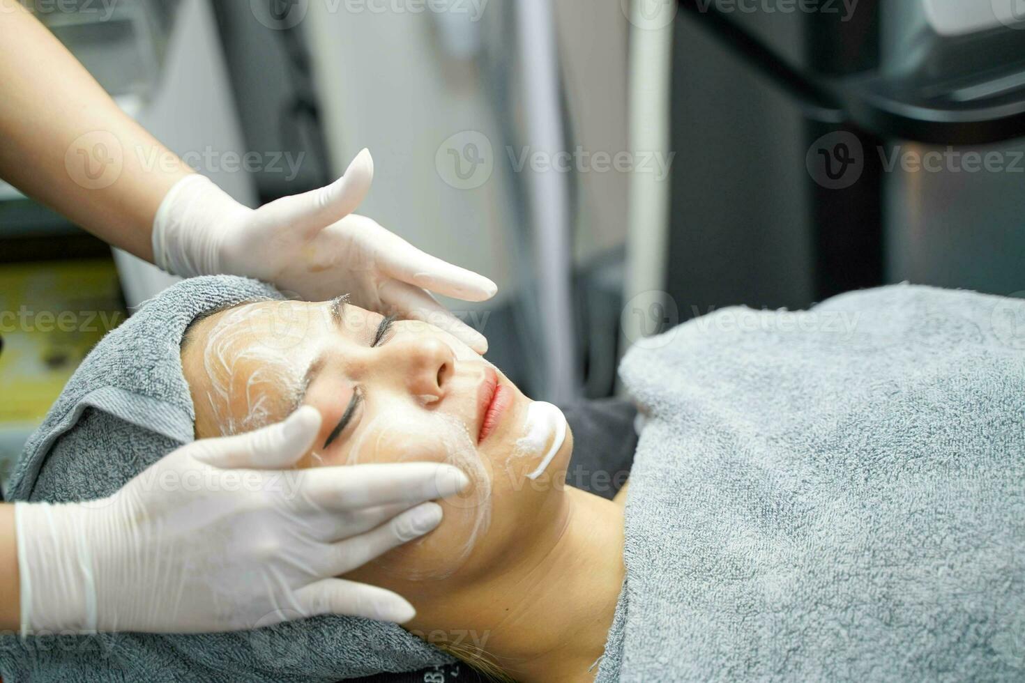 jovem mulher de beleza em toalha fazendo massagem facial com esfoliante facial orgânico. foto