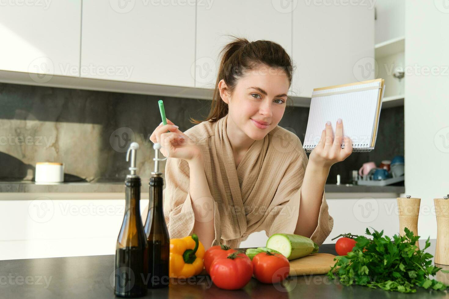 retrato do mulher cozinhando dentro a cozinha, lendo dela notas, verificação receita enquanto preparando refeição, fazer café da manhã salada, escrevendo baixa mercearia Lista foto