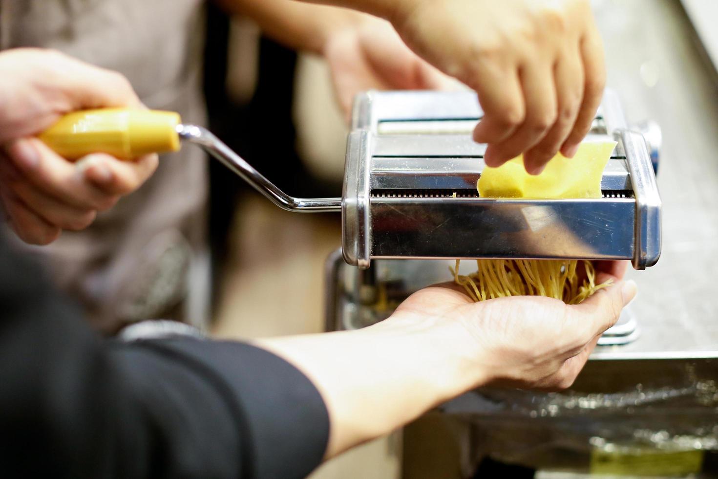 chef fazendo macarrão com máquina, macarrão caseiro fresco foto