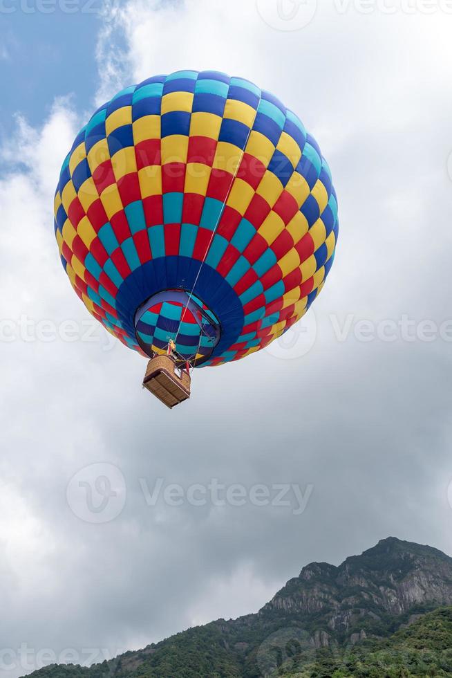 feche balões de ar quente com manchas vermelhas, amarelas e azuis na montanha foto