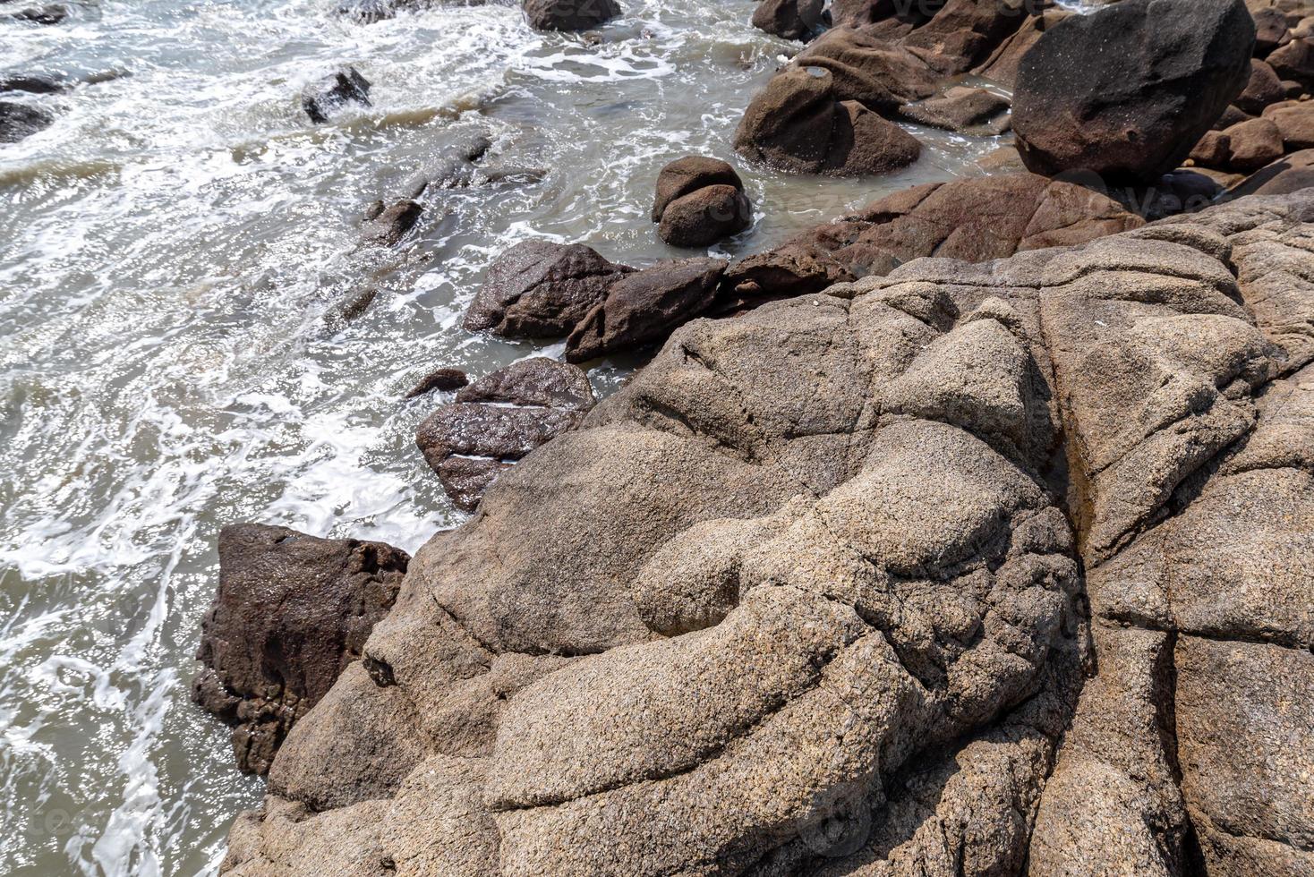 as ondas brancas batem contra as pedras pretas foto