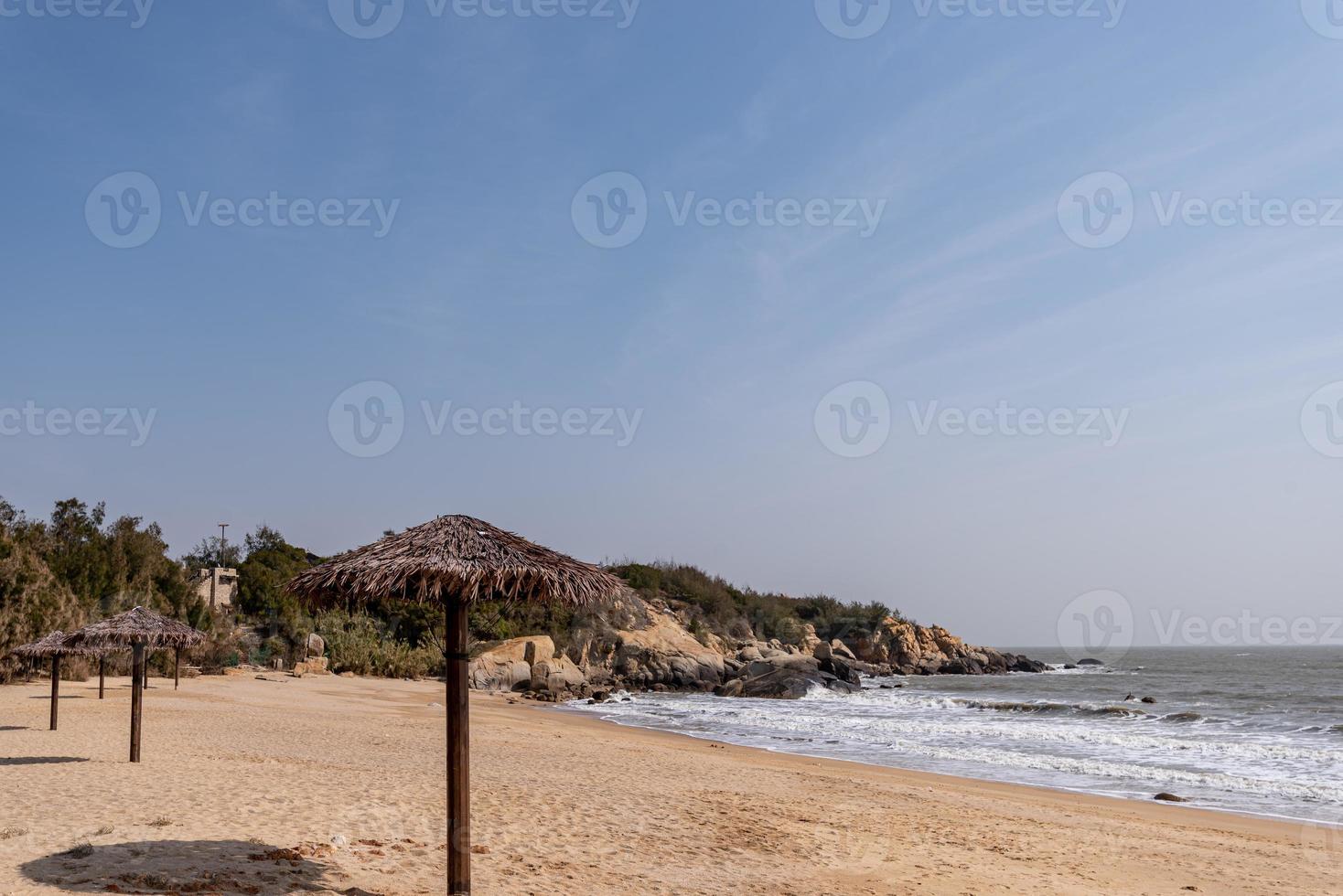 há guarda-sóis de grama na praia no verão foto