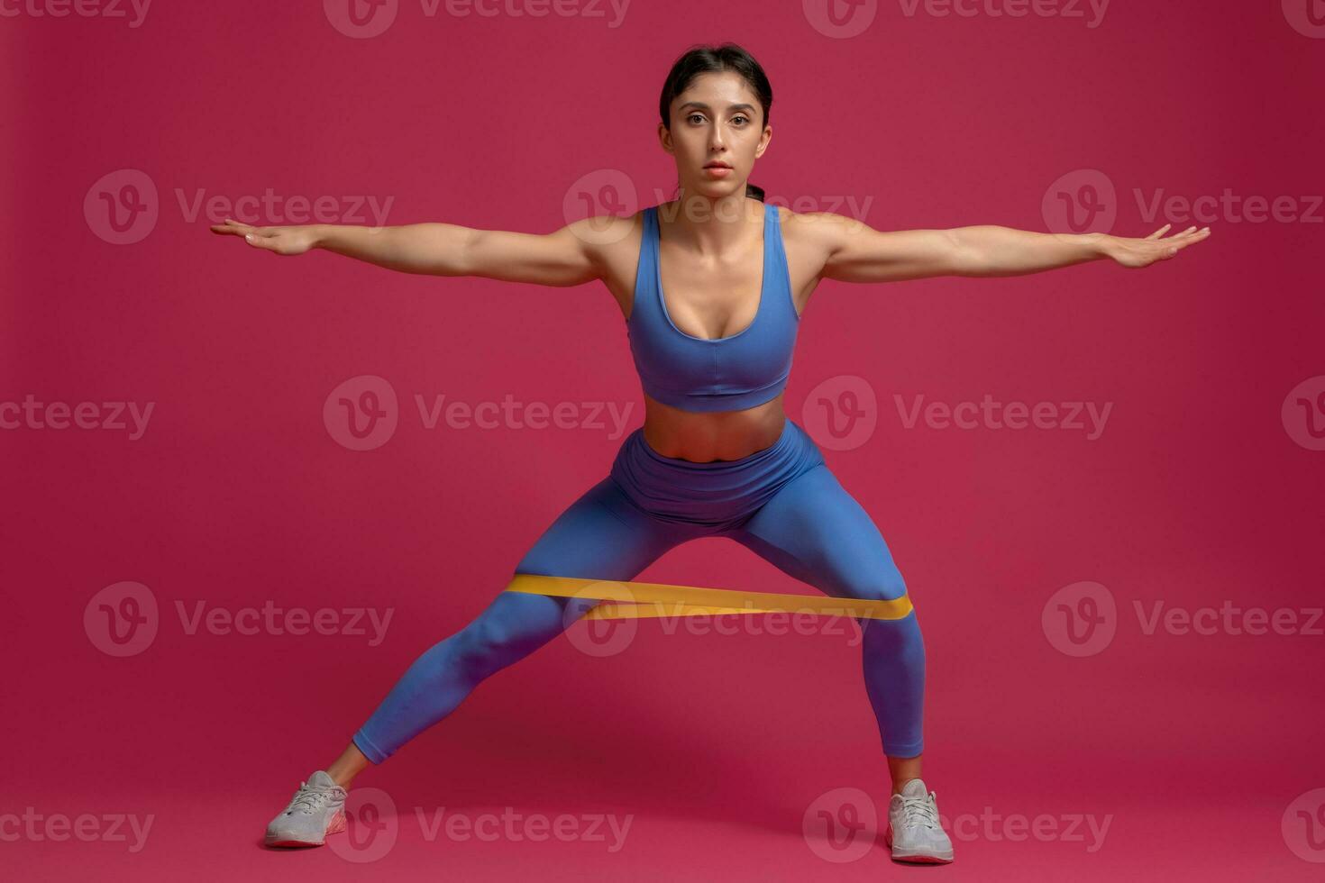 menina realizando resistência banda lateral estocada em marrom fundo foto