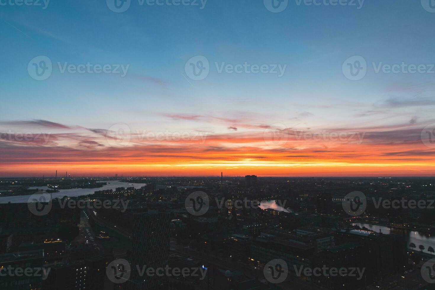 aéreo Visão do vida noturna dentro a moderno cidade do Rotterdam dentro a Holanda. vermelho brilho a partir de a configuração Sol dentro a fundo foto