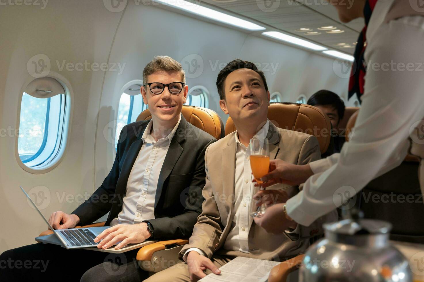 voar atendente servindo laranja suco para homem de negocios em avião foto