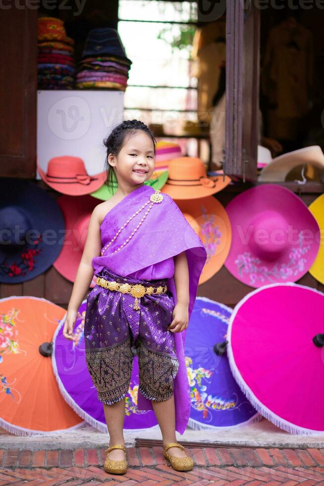 pequeno ásia menina dentro tailandês período vestir em pé com colorida guarda-chuva foto