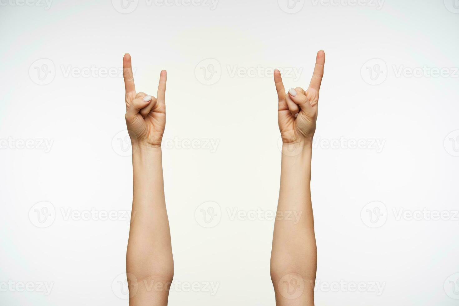 fechar-se do jovem mulher mãos mostrando pesado metal e Rocha gesto enquanto posando contra branco fundo. corpo língua e sinais conceito foto
