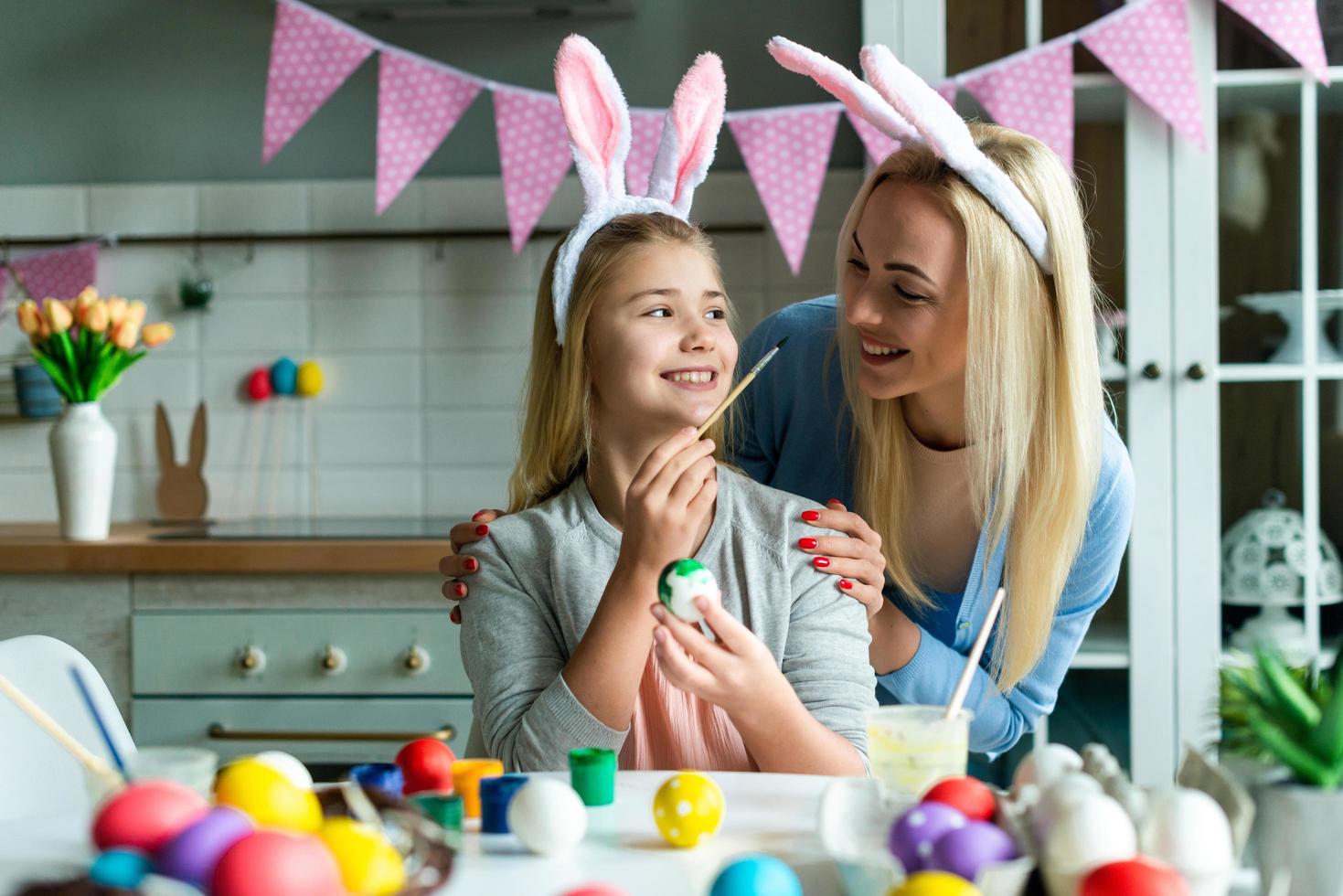 feliz feriado. uma mãe e sua filha estão pintando ovos. família se preparando para a Páscoa. criança menina bonitinha está usando orelhas de coelho. foto