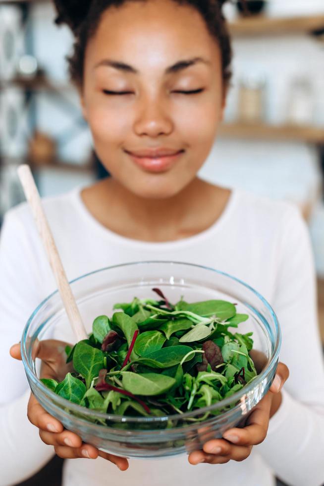 linda jovem segurando uma deliciosa salada com os olhos fechados, aproveitando o momento. conceito de alimentação saudável foto