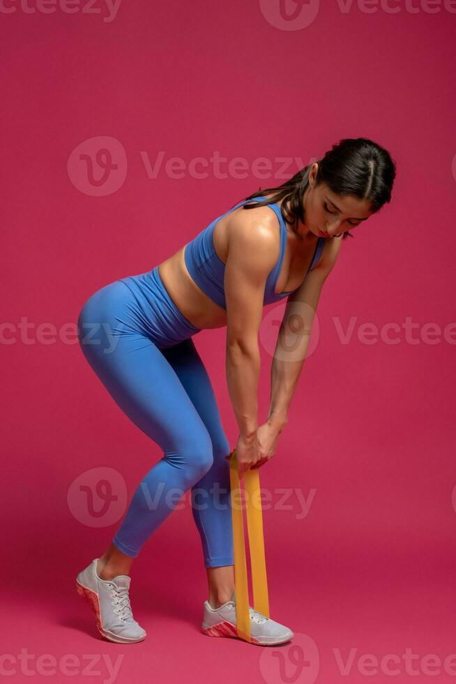 mulher fazendo resistência banda levantamento terra em marrom fundo foto