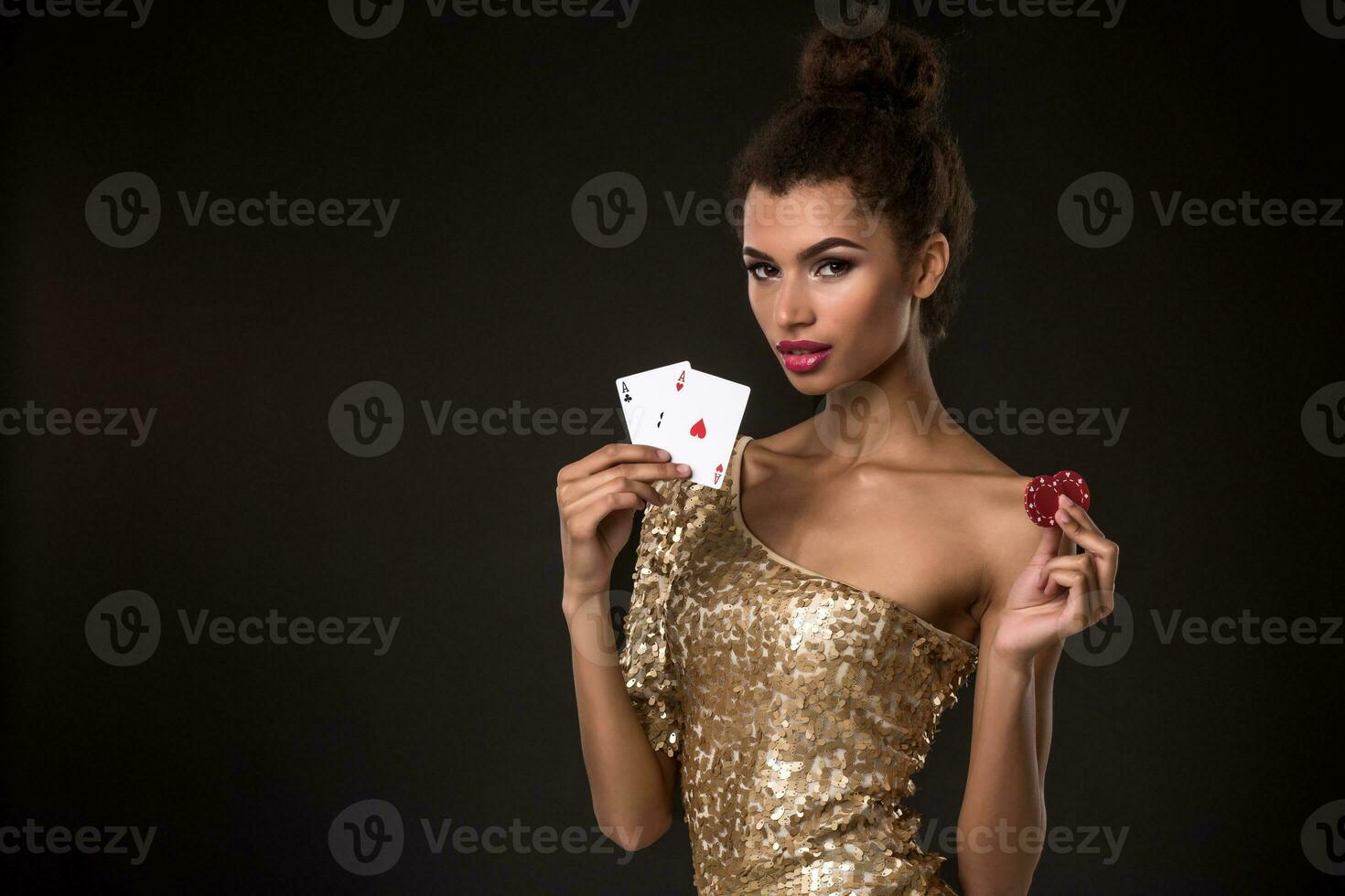 mulher ganhando - jovem mulher dentro uma elegante ouro vestir segurando dois ases e dois vermelho salgadinhos, uma pôquer do ases cartão combinação. foto