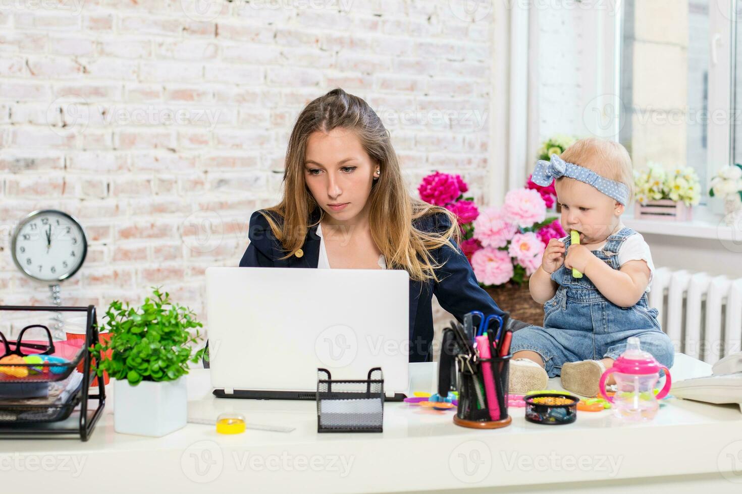 alegre jovem lindo empresária olhando às computador portátil enquanto sentado às dela trabalhando Lugar, colocar com dela pequeno filha foto