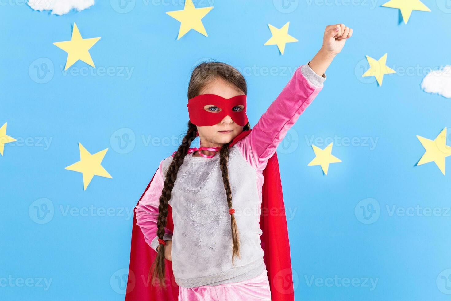 pequeno criança tocam Super heroi. criança em a fundo do brilhante azul muro. foto