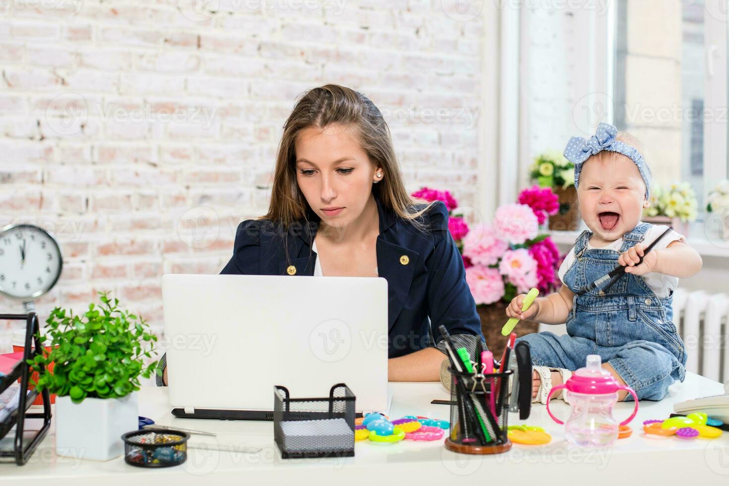 alegre jovem lindo empresária olhando às computador portátil enquanto sentado às dela trabalhando Lugar, colocar com dela pequeno filha foto