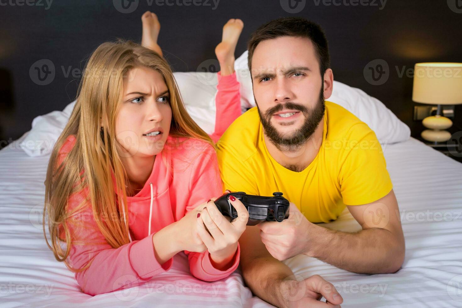 jovem casal tendo jogando videogames dentro cama foto