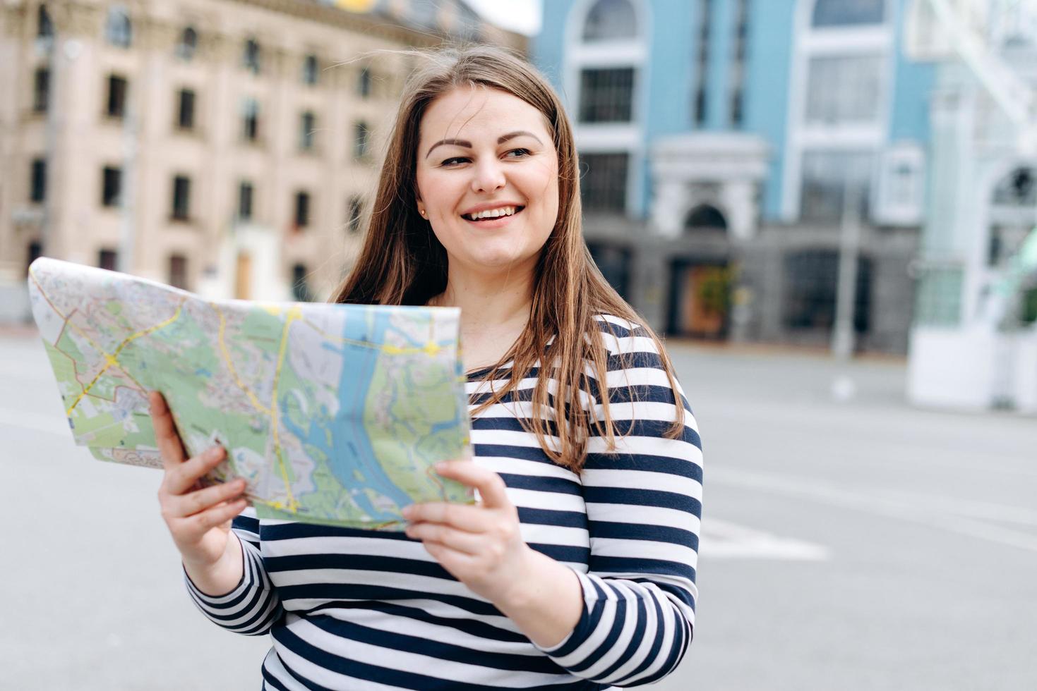 garota tem um mapa nas mãos. turista mulher estudar o mapa de localização foto