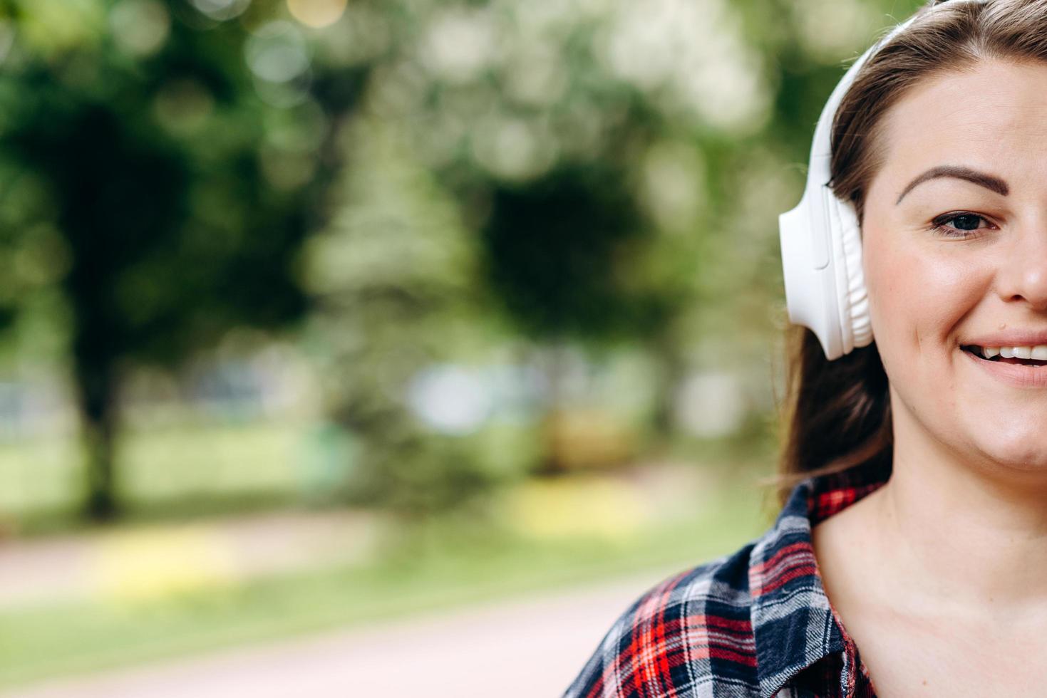 a foto mostra metade do rosto de uma mulher bonita e sorridente usando fones de ouvido brancos