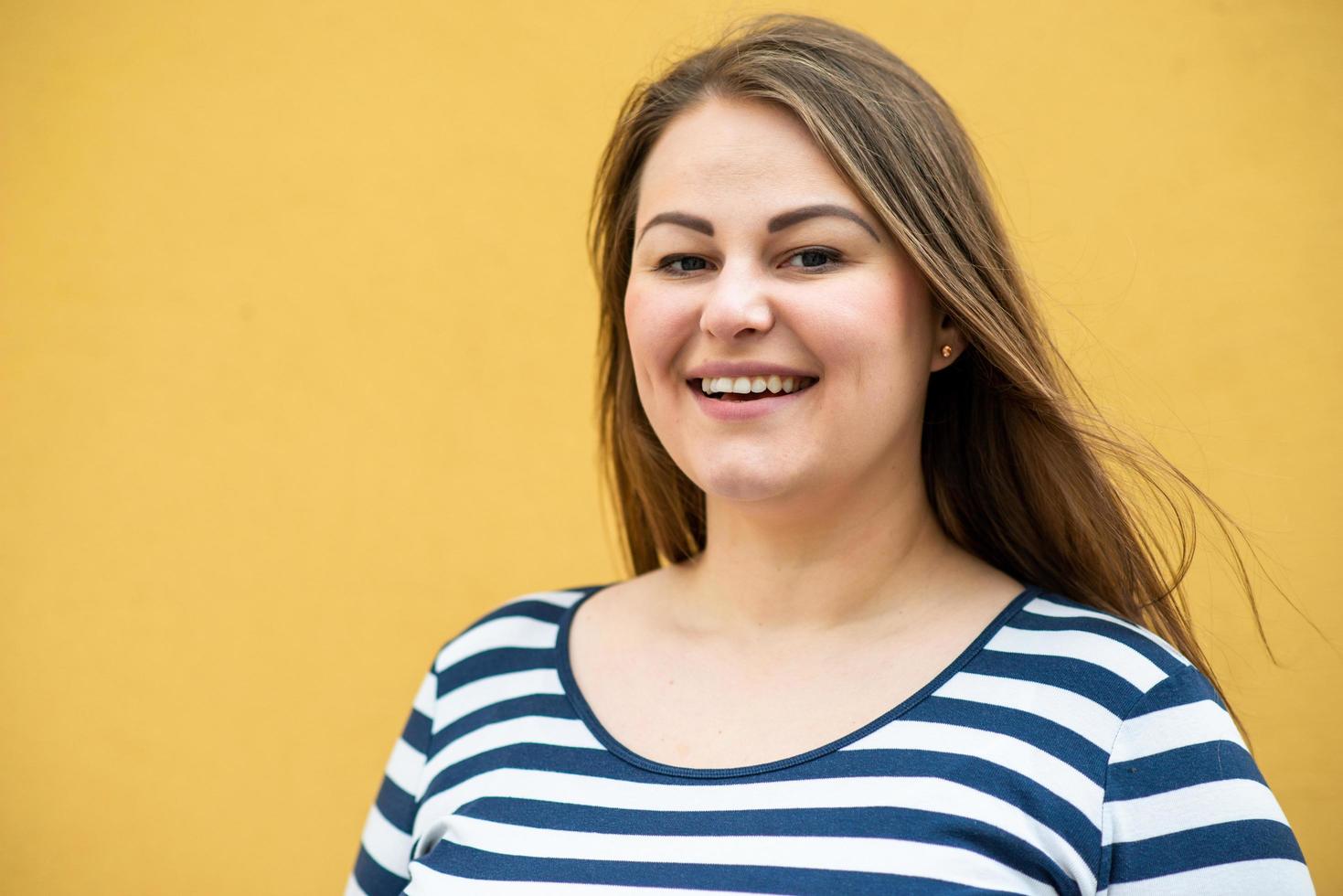 mulher feliz com excesso de peso posando isolada sobre fundo laranja foto