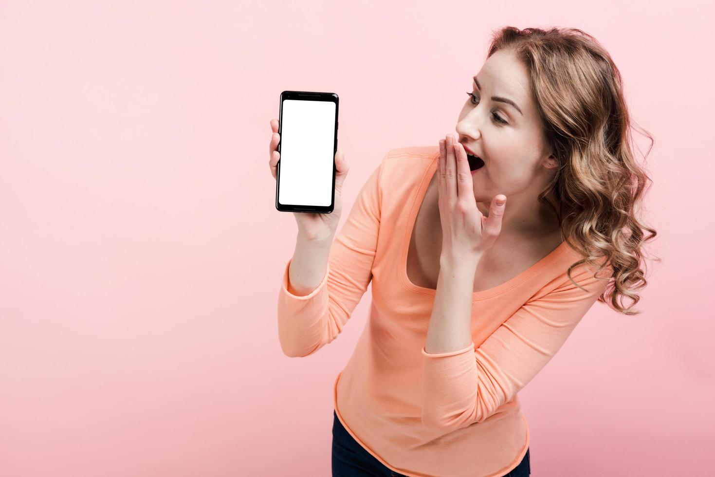 jovem chocada olhando para a tela do telefone. lugar para publicidade foto